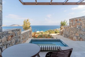 Zona de piscina con muros de piedra y vistas al mar.