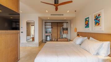 Una habitación de hotel moderna con una cama grande, cabecera de madera, ventilador de techo y obras de arte en las paredes.