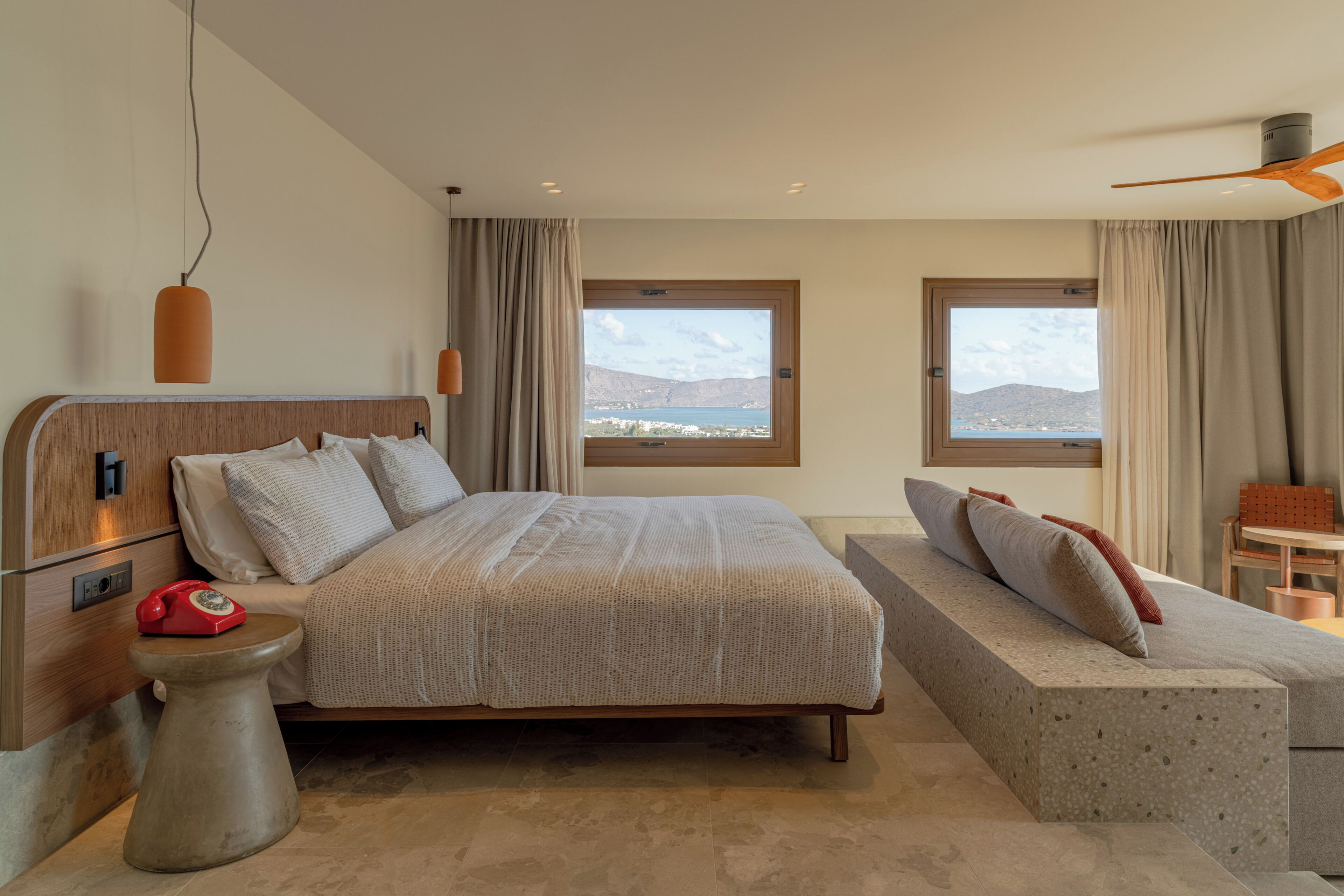 Un dormitorio con una cama, un sofá, un teléfono y dos ventanas con vistas.
