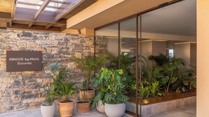 A modern building entrance with a stone wall and potted plants.
