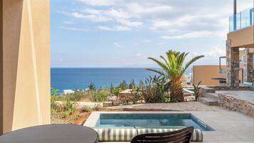 A poolside area with a view of the sea, a table, and a chair.
