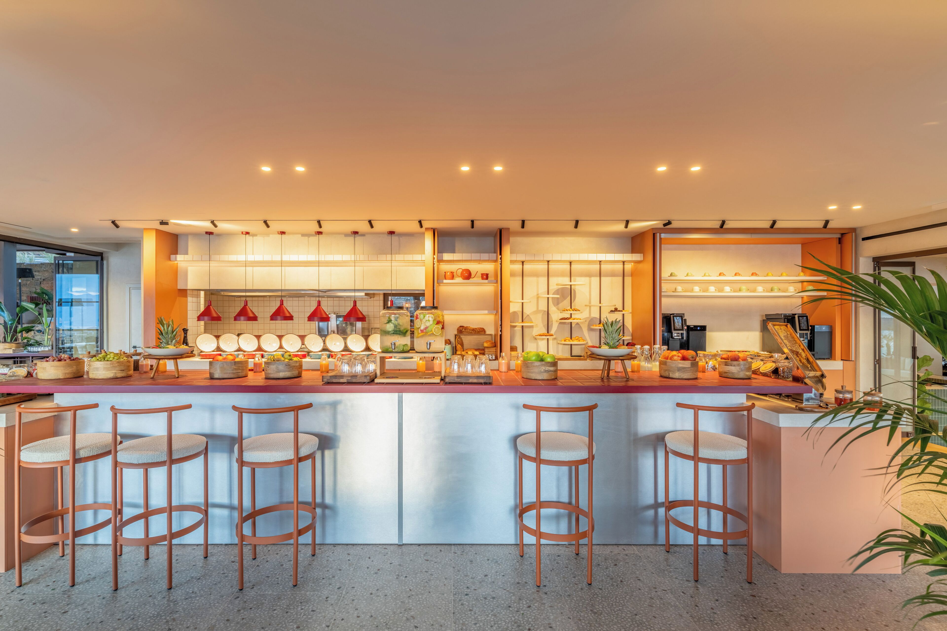 Una cucina moderna con isola centrale, sgabelli da bar e diversi elettrodomestici.