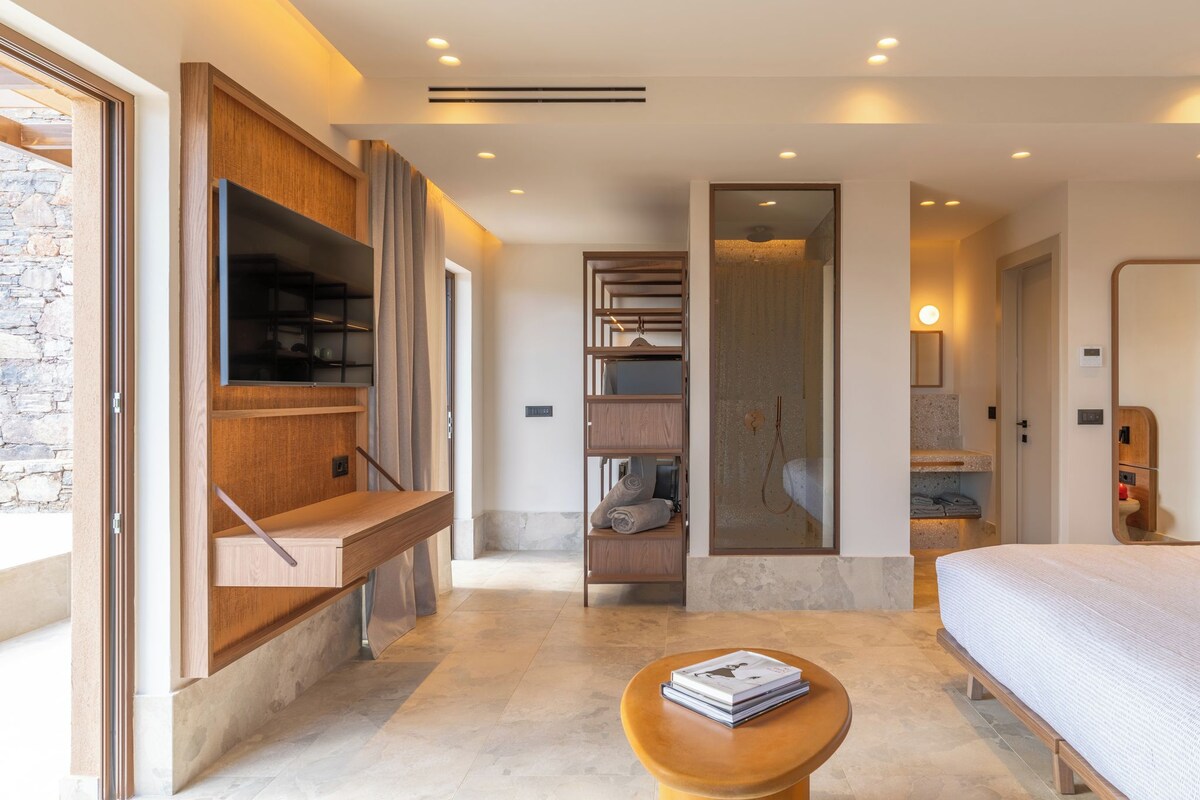 A modern bedroom with a bed, a wooden bench, a small table, and built-in shelving.