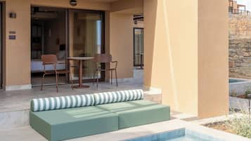 A modern hotel with a swimming pool, outdoor seating, and a glass-enclosed balcony.