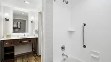 A modern bathroom with a white sink, dark wooden vanity, and a walk-in shower with a grab bar.