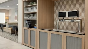 A modern hotel room with a kitchenette, a seating area with a sofa and chairs, and a TV mounted on the wall. - Homewood Suites by Hilton Denver West Lakewood (Lakewood)