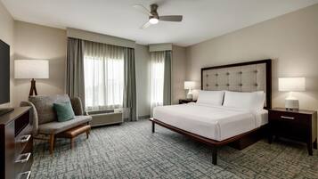 A hotel room with a bed, a chair, a desk, a television, and a ceiling fan.