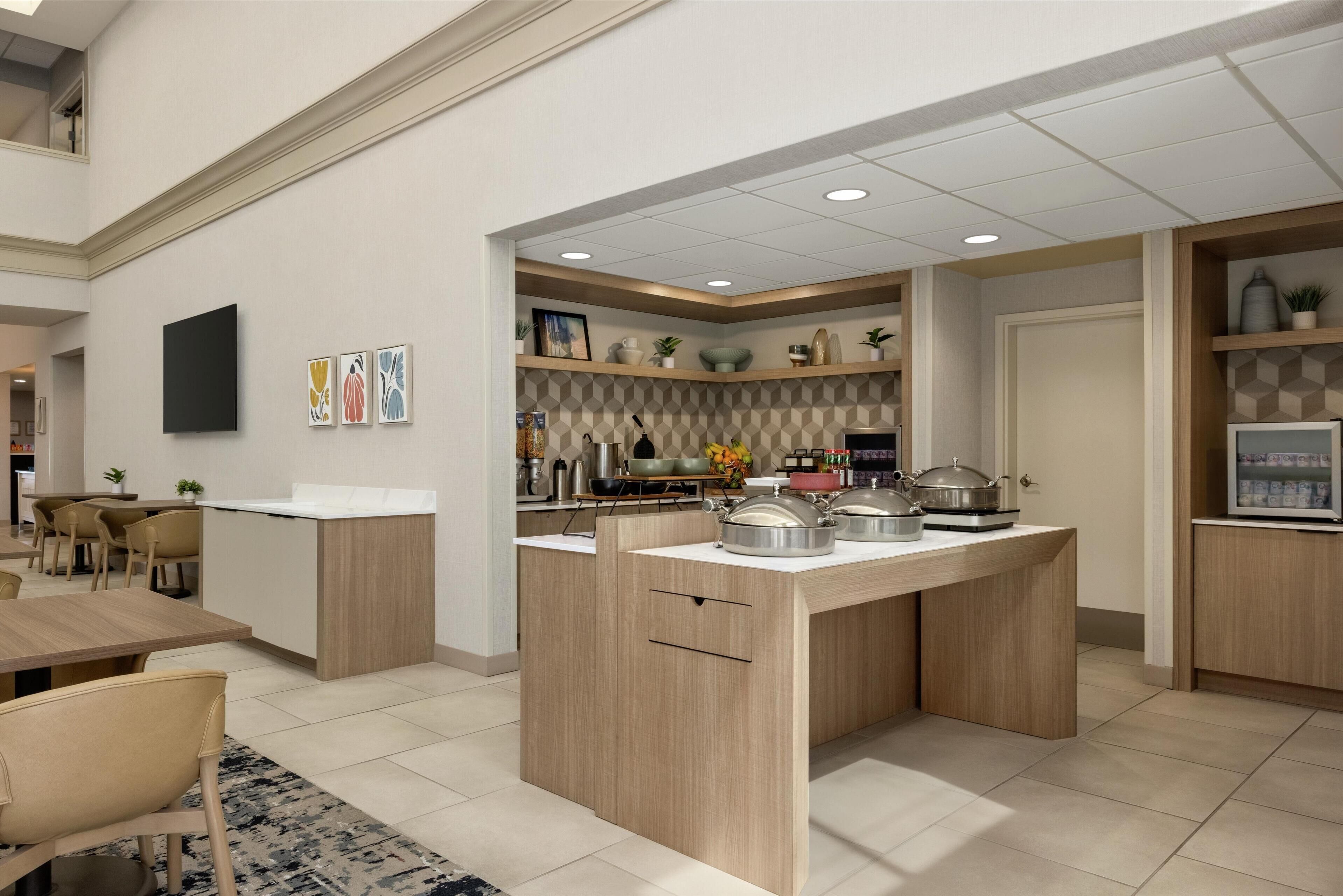 Una cocina moderna con una isla central, armarios de madera y un comedor con sillas.