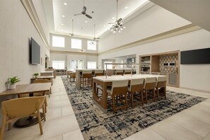 A spacious kitchen with modern appliances, a dining area with a large table and chairs, and a ceiling fan.