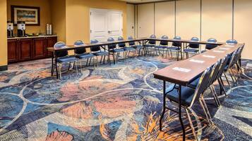 A conference room with a long table, chairs, and a carpeted floor.