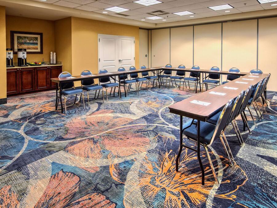 A conference room with a long table, chairs, and a carpeted floor.