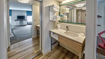 Un baño moderno con piso de madera, un espejo grande y un lavamanos con toallero superior.