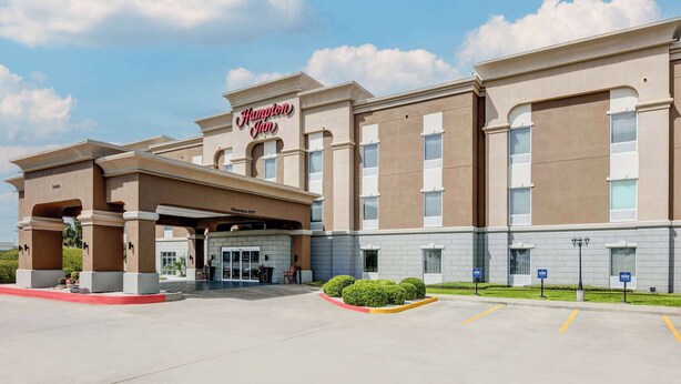 A Hampton Inn hotel with a covered entrance, multiple windows, and a parking lot.