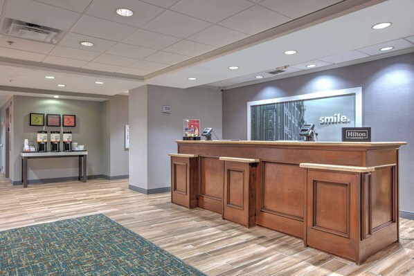 A reception desk with a 'smile' sign, a clock, and a 'Hilton' sign.