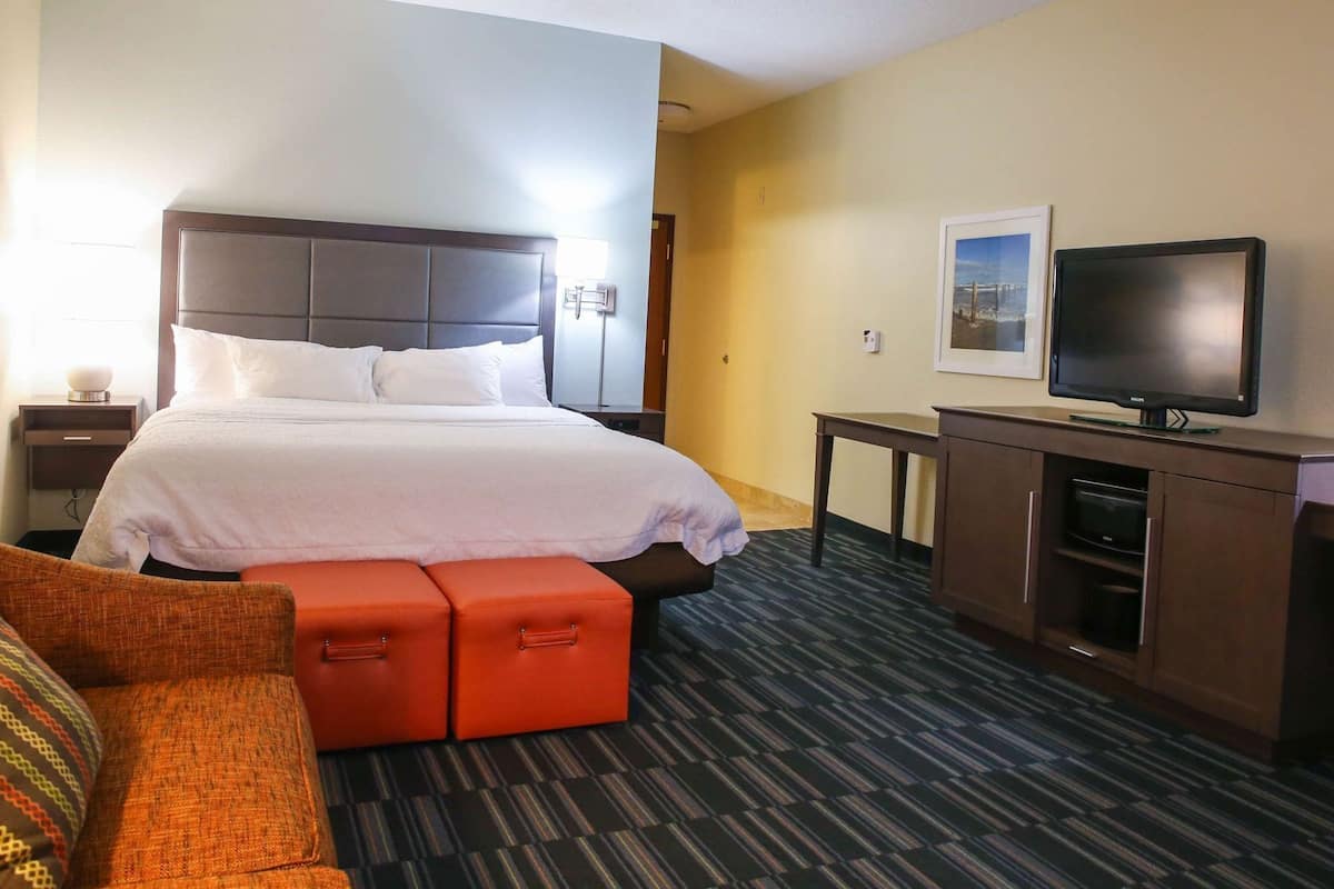 A hotel room with a bed, a television, a desk, and a couch.