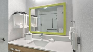 Un baño moderno con un lavamanos blanco, un espejo con marco verde, un perchero y una zona de ducha.