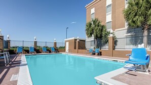 A swimming pool with blue chairs and a building in the background.