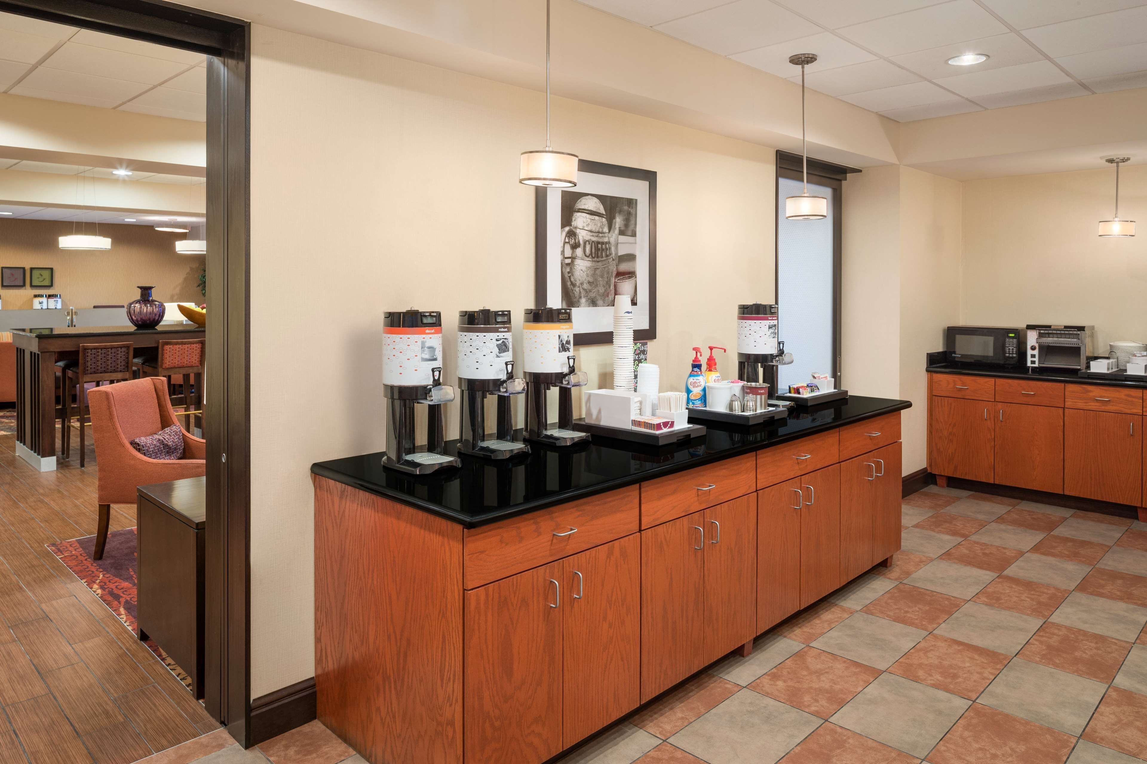 A modern kitchen with a coffee station, wooden cabinets, and a tiled floor.