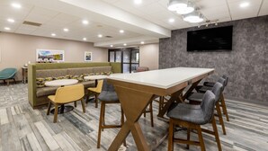 A conference room with a long table, several chairs, a sofa, and a television on the wall. - Hampton Inn Belle Vernon (Belle Vernon)