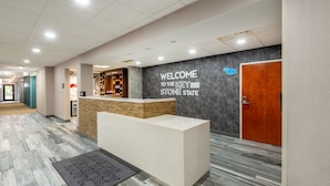 A reception area with a reception desk, a welcome sign, and a wooden door. - Hampton Inn Belle Vernon (Belle Vernon)
