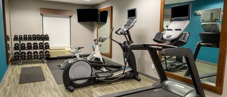 A gym with treadmills, an elliptical, and a rack of dumbbells.