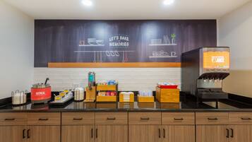 A kitchen area with a coffee machine, a chalkboard with a baking theme, and various kitchen utensils.