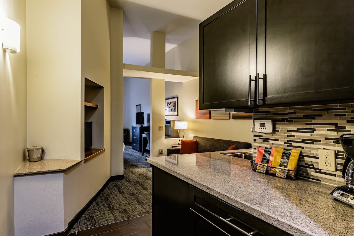 A modern kitchen with granite countertops, dark cabinetry, and a tiled backsplash.