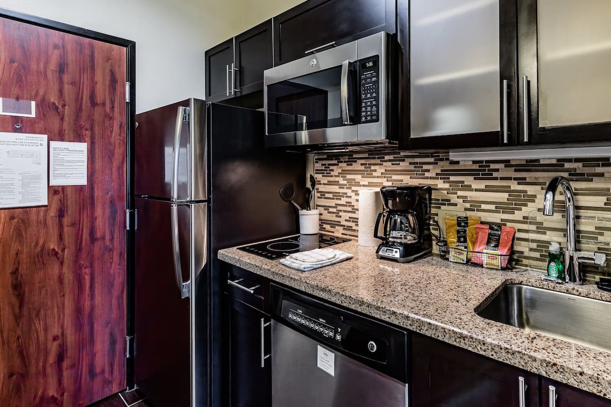 A modern kitchen with stainless steel appliances, a granite countertop, and a tiled backsplash.