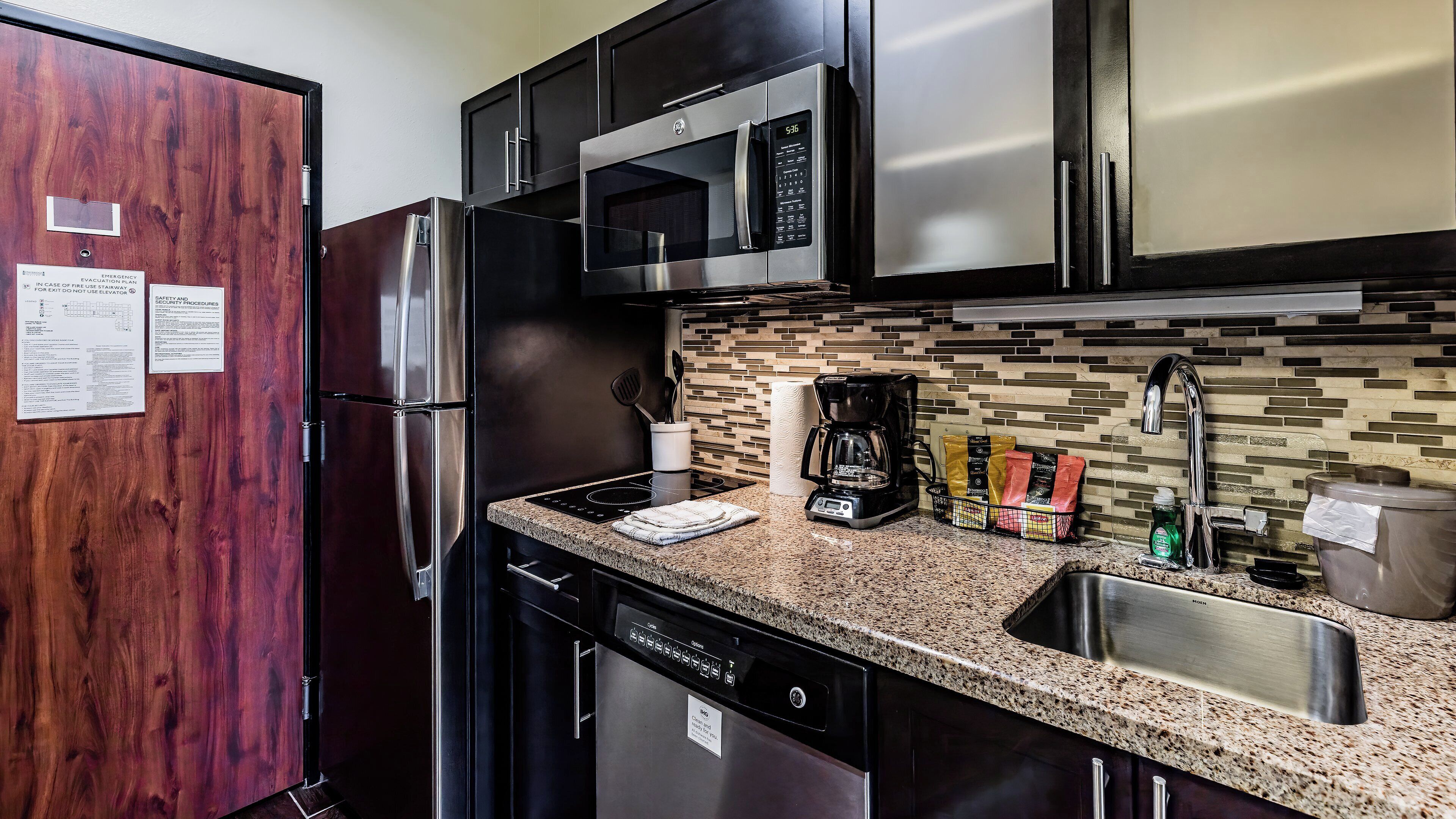 A modern kitchen with stainless steel appliances, a granite countertop, and a dishwasher.