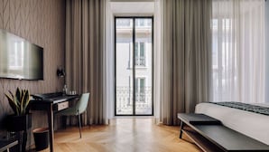 A modern hotel room with a large bed, a desk with a chair, a TV, and a balcony with curtains. - Hotel X Hotel Avenida Liberdade, a Member of Design Hotels (Lisbon)