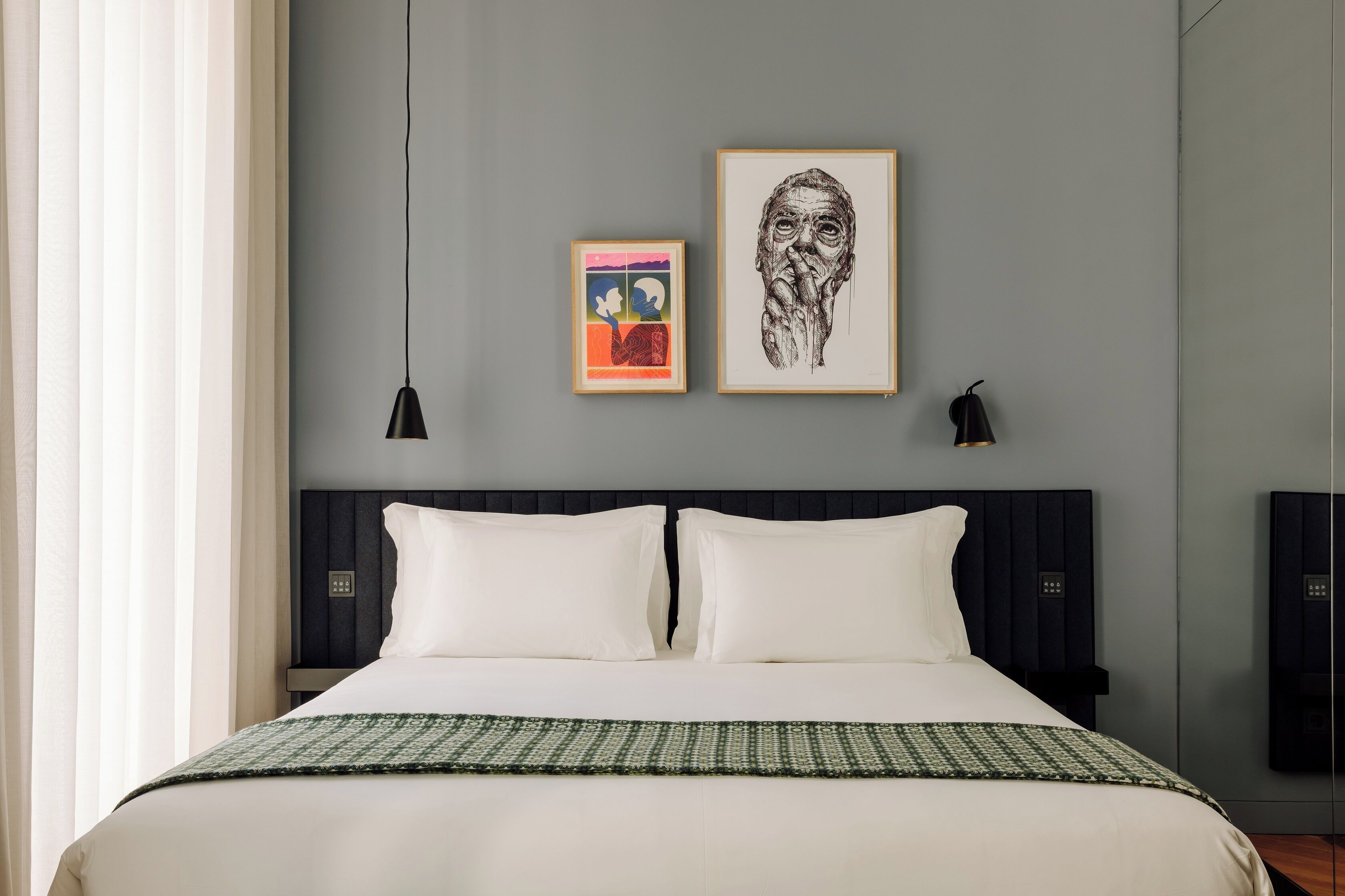 A modern bedroom with a large bed, two bedside tables, and artwork on the wall.