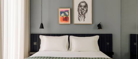 A modern bedroom with a large bed, two bedside tables, and artwork on the wall.