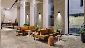 A modern lobby with a sofa set, a coffee table, and a small stool. There are potted plants and a large window with a view of the street. - Hotel X Hotel Avenida Liberdade, a Member of Design Hotels (Lisbon)