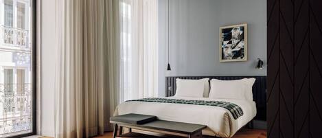 A modern bedroom with a bed, bench, and artwork on the wall.