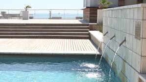 A pool with clear water, steps leading down to the water, and a view of the sea in the background. - Sunstays Lagoon Beach (Cape Town)
