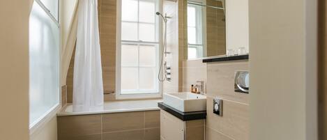 A modern bathroom with a bathtub, a shower, a sink, and a toilet.