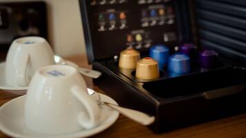 A coffee maker with multiple cups and a spoon on a table.