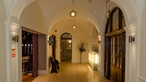 Un couloir d’hôtel avec des plafonds en arc de cercle, un comptoir de réception et un espace salon.