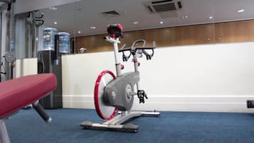 A gym with a stationary bike, a bench, and water dispensers.