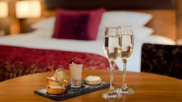 A dining table with a dessert plate, two glasses of white wine, and a dessert with a raspberry topping.