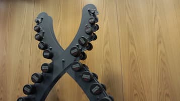 Musta, X-kirjaimen muotoinen penkkipunnituslaite, jossa on useita painolevyjä, joissa lukee ”Hammer Strength”.