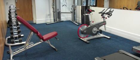 A gym with cardio equipment, weight machines, and a bench.