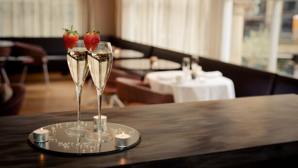 Un coin bar avec deux coupes à champagne garnies de fraises, une bougie et un plateau avec de petites bougies.