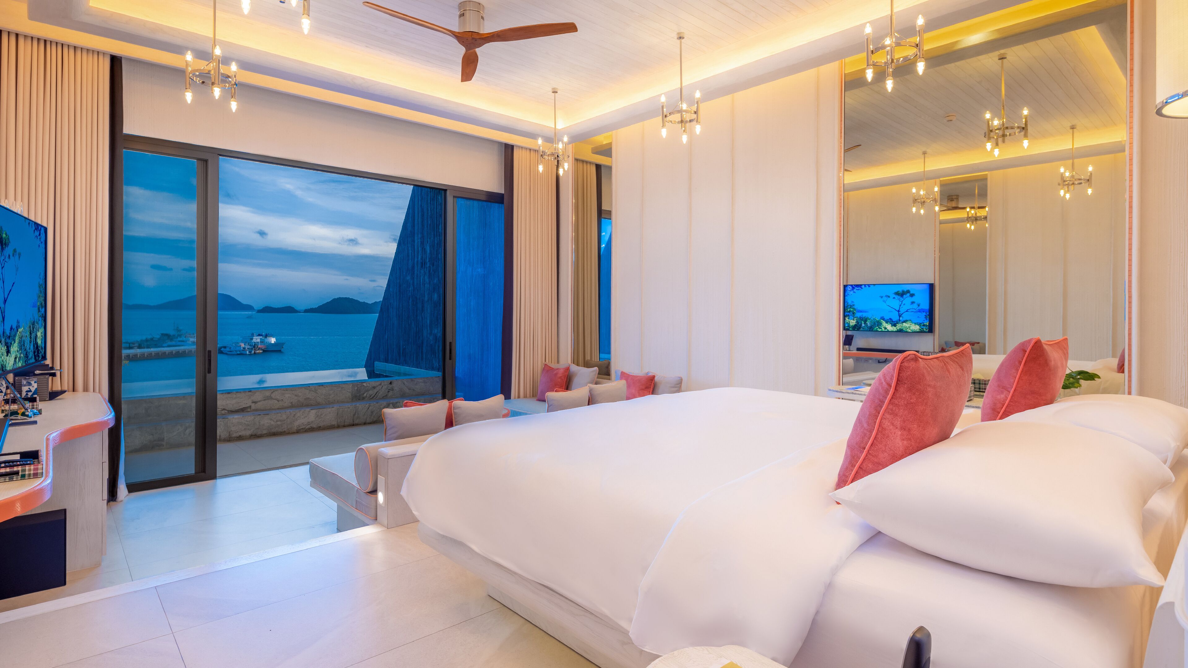 A modern hotel room with a large bed, a TV, and a balcony with a sea view.