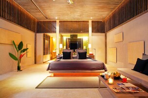 A modern hotel room with a large bed, a seating area, and a view of the city.