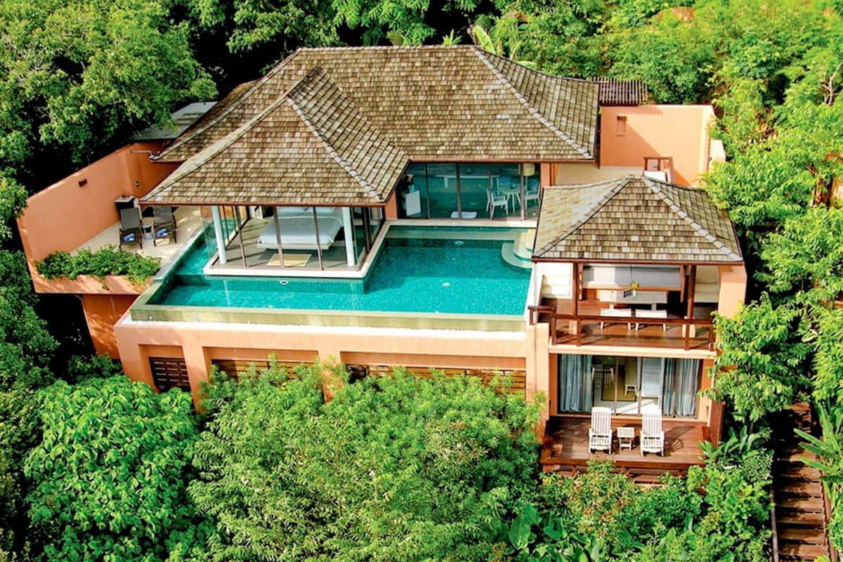 A large house with a swimming pool, multiple decks, and lush greenery surrounding it.