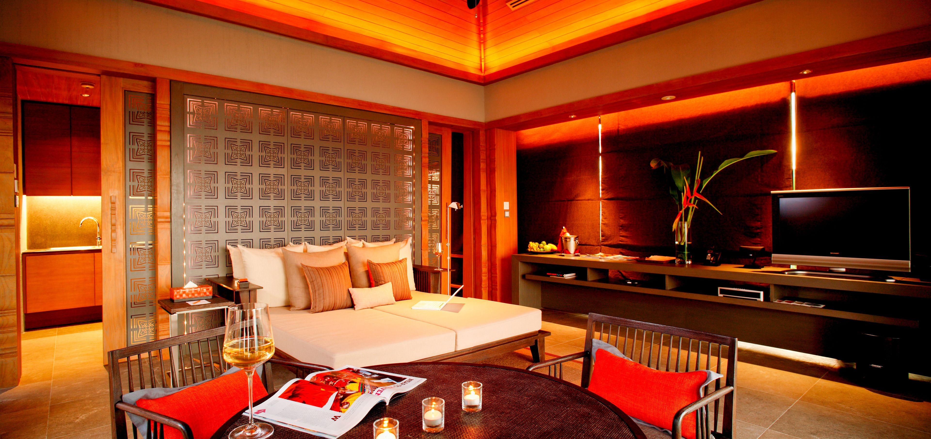 Une chambre d’hôtel moderne équipée d’un canapé, d’une table à manger avec des magazines et d’un téléviseur.