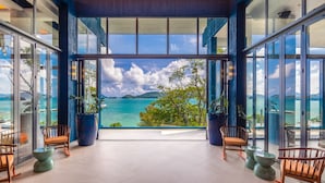 A spacious terrace with a view of a turquoise sea and distant mountains, furnished with wooden chairs and large potted plants. - Sri Panwa Phuket Luxury Pool Villa Hotel (Wichit)