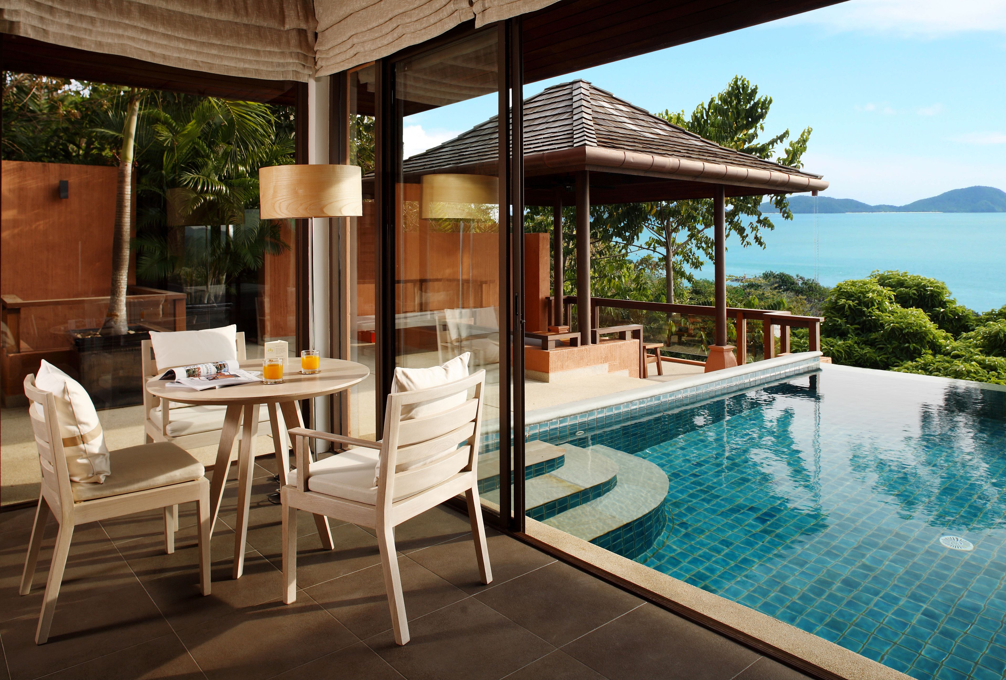 Ein Poolbereich mit Tisch und Stühlen, einer Pergola und Blick auf das Meer.
