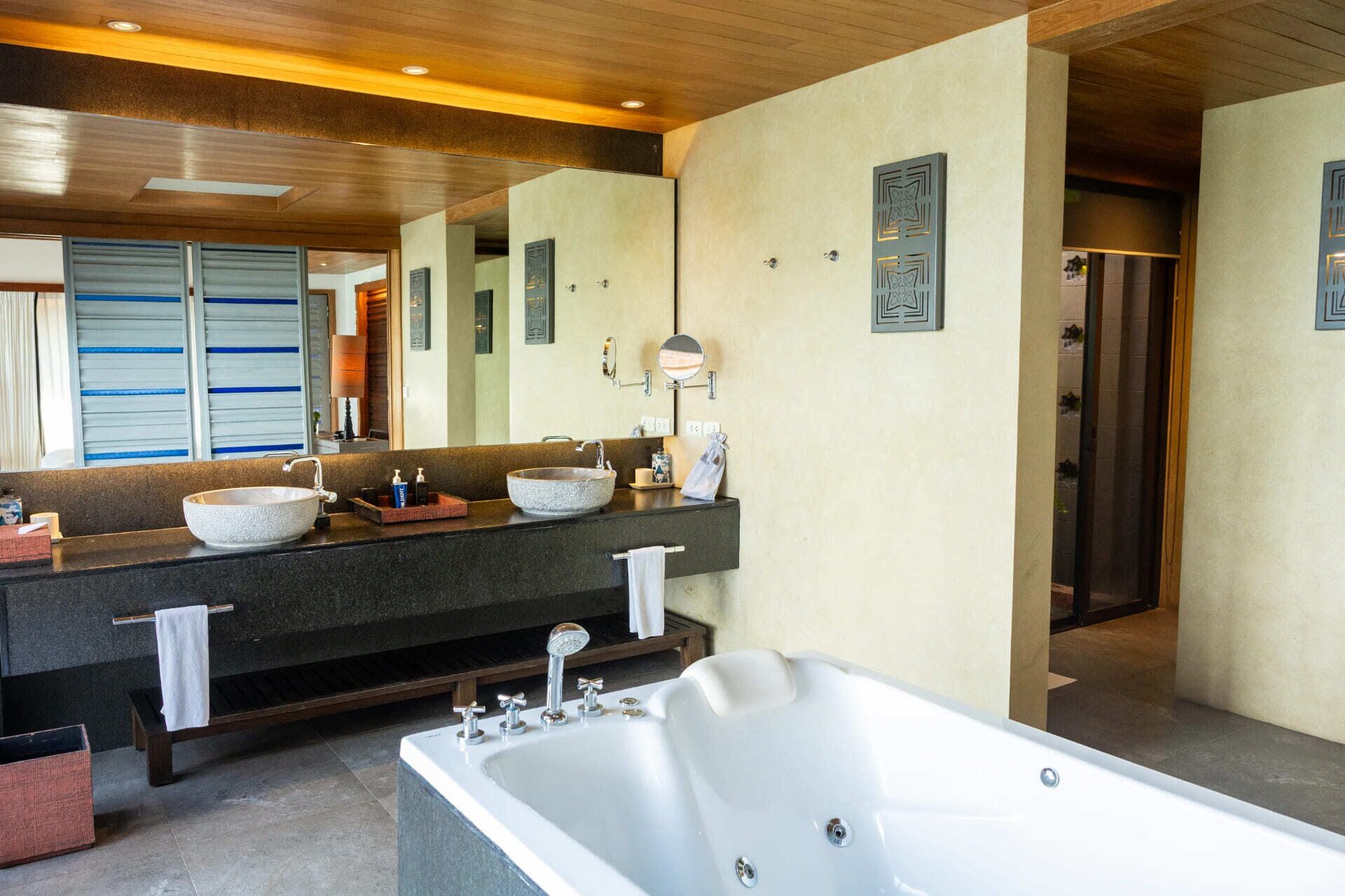A modern bathroom with a large bathtub, two sinks with vessel basins, and a large mirror.